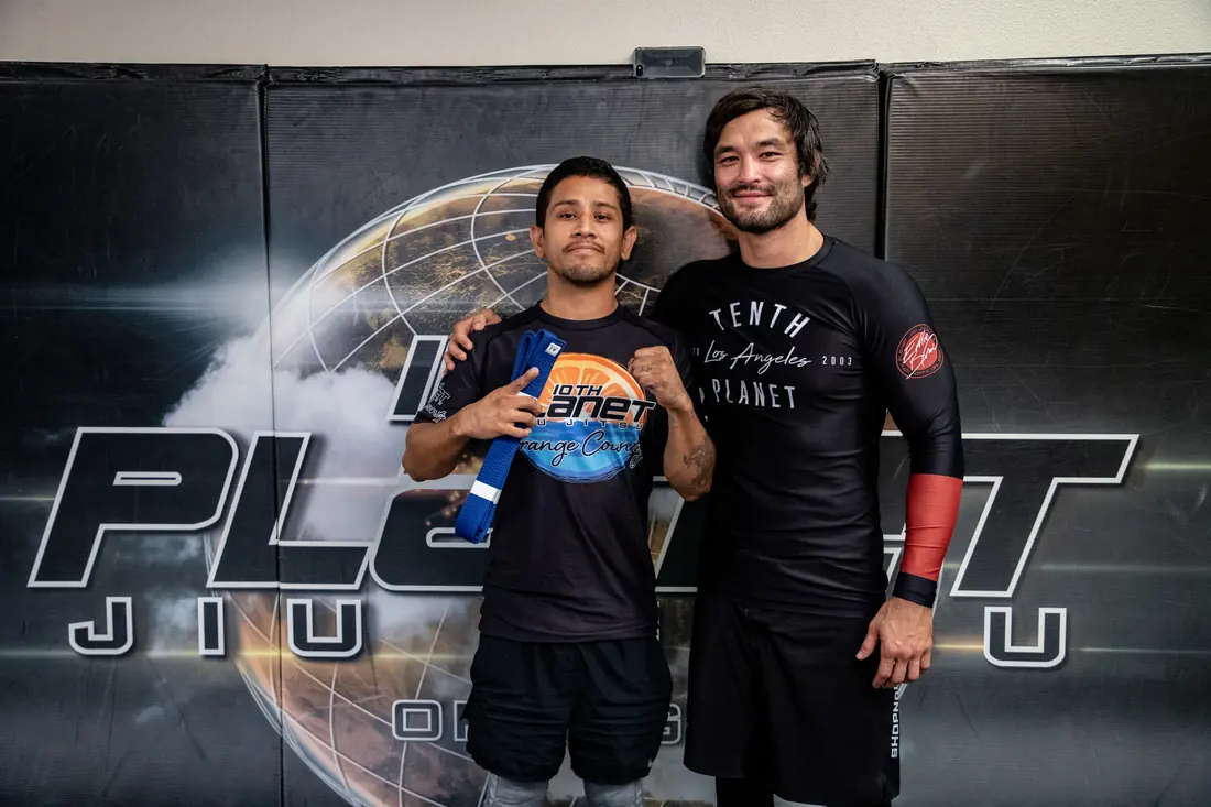 Student promoted with his new belt beside his coach at 10th Planet Orange